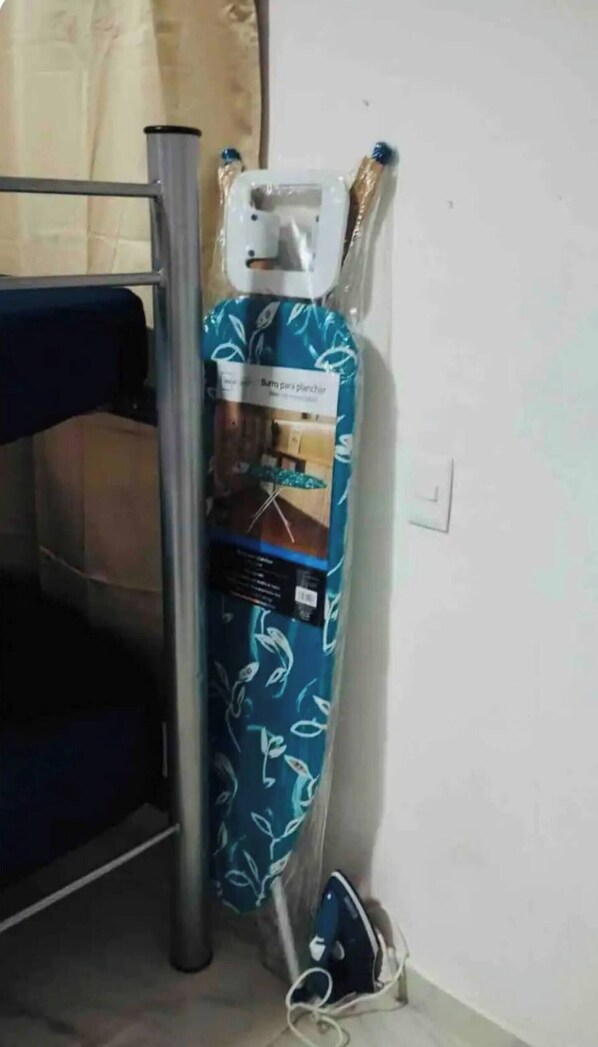 A room with a bunk bed, a standing heater, and a packaged item on the floor.