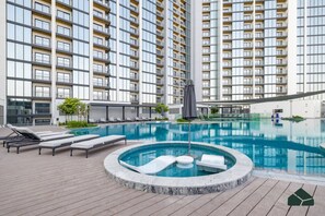 Un hôtel moderne doté d’une piscine sur le toit, de chaises longues et d’un jacuzzi circulaire.