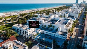 Un paysage urbain côtier avec un hôtel imposant doté d’une piscine sur le toit et offrant une vue sur la plage.