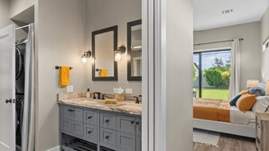 A modern bathroom with dual sinks, a large mirror, and a view of the outdoors.