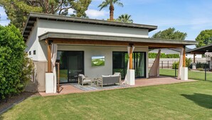 A modern house with a covered patio, outdoor seating, and a large window.