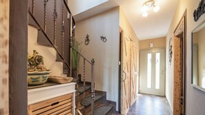 A wooden staircase with a decorative bowl on the landing, a mirror on the wall, and a door leading to another room.