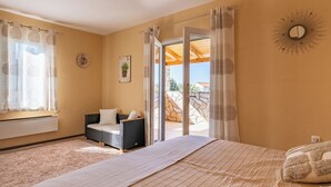 A bedroom with a large bed, a sofa, and a view of the outside.