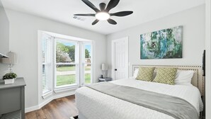 A bedroom with a bed, a ceiling fan, a painting, and a window with blinds. - Flower Mound Manor - Modern 3BR New Construction (Flower Mound)