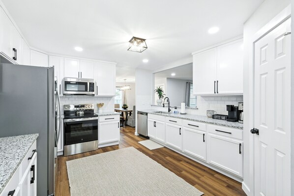 A modern kitchen with white cabinetry, stainless steel appliances, and a granite countertop.