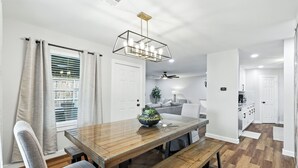 A modern dining area with a wooden table, bench seating, and a ceiling fan. - Flower Mound Manor - Modern 3BR New Construction (Flower Mound)