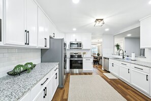 A modern kitchen with white cabinets, stainless steel appliances, and a granite countertop.