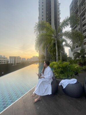 A person sitting by a pool with a cityscape in the background. -  (Brand new 30sqm Studio unit) 15th floor @ Baseline Prestige (Cebu City)