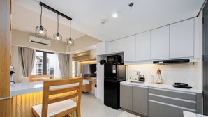 Eine moderne Küche mit weißen Schränken, einem schwarzen Kühlschrank und Holzstühlen.