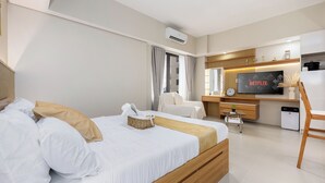 Ein modernes Hotelzimmer mit einem großen Bett, einem Fernseher, einem Schreibtisch und einem kleinen Badezimmer.