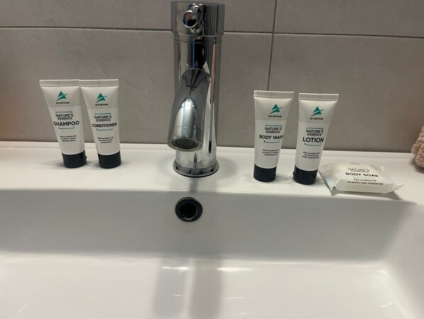 A bathroom sink with a chrome faucet, four tubes of Avistar Nature's Essence products, and a small packet of body soap.