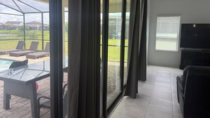 Un salón espacioso con un amplio ventanal corredera que da a un patio.
