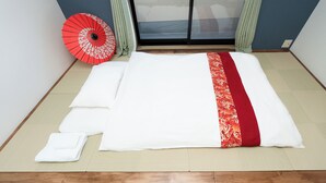 A neatly made bed with white and red bedding, a red and white patterned umbrella, and a sliding glass door with curtains. - FUKA KAZEHANA MINBAKU OOMORIHONCHO｜11 min. direct access to Haneda Airport, private house for rent (大田区大森本町)