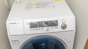 A white Sharp washing machine with a digital display, control panel, and a transparent door. - FUKA KAZEHANA MINBAKU OOMORIHONCHO｜11 min. direct access to Haneda Airport, private house for rent (大田区大森本町)