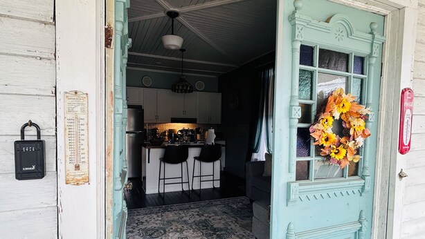 Une cuisine avec des armoires blanches, un luminaire suspendu et une guirlande décorative accrochée à la porte.