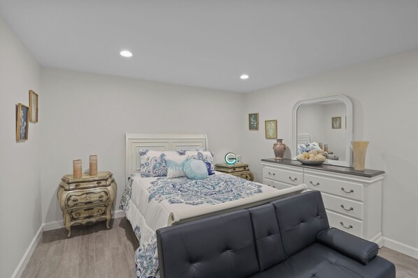 A bedroom with a bed, nightstands, a dresser, a mirror, and a chair.