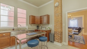A modern kitchen with a central island, bar stools, wooden cabinets, and a brick accent wall. - 3 King BedRooms Spacious & Serene House, Private Yard and Parking in Chattanooga (Chattanooga)