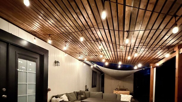 Uma sala de estar aconchegante com teto de madeira, um sofá seccional grande e um tapete estampado.