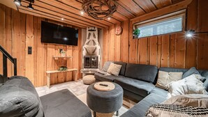 A cozy living room with a fireplace, a large flat-screen TV, and a comfortable seating area. - Jukola Juhani by Aavalevi Holidays (Levi)