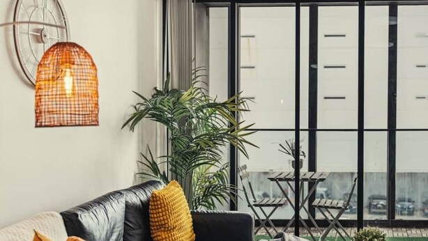 Una sala de estar moderna con un sofá de cuero negro, una mesa de comedor con un cuenco de fruta y un ventanal con vistas a la ciudad.
