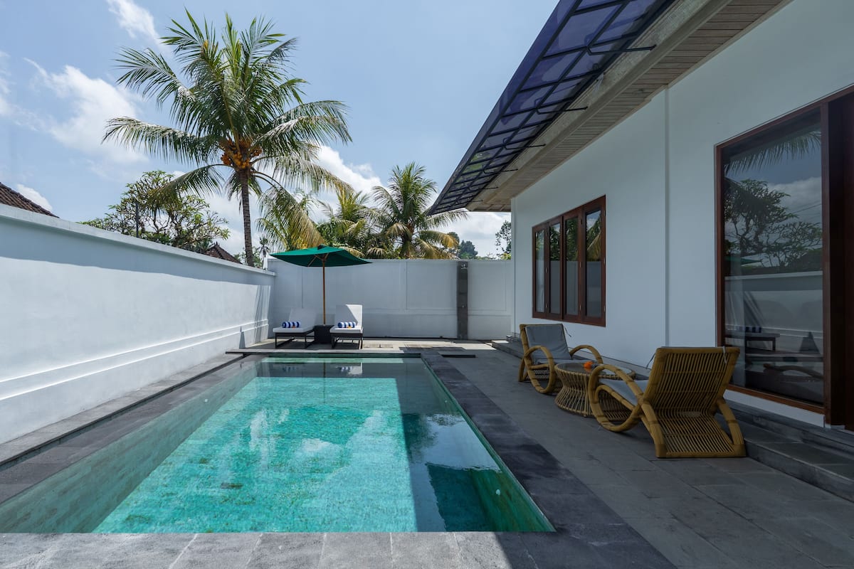 A swimming pool with lounge chairs and a pergola.