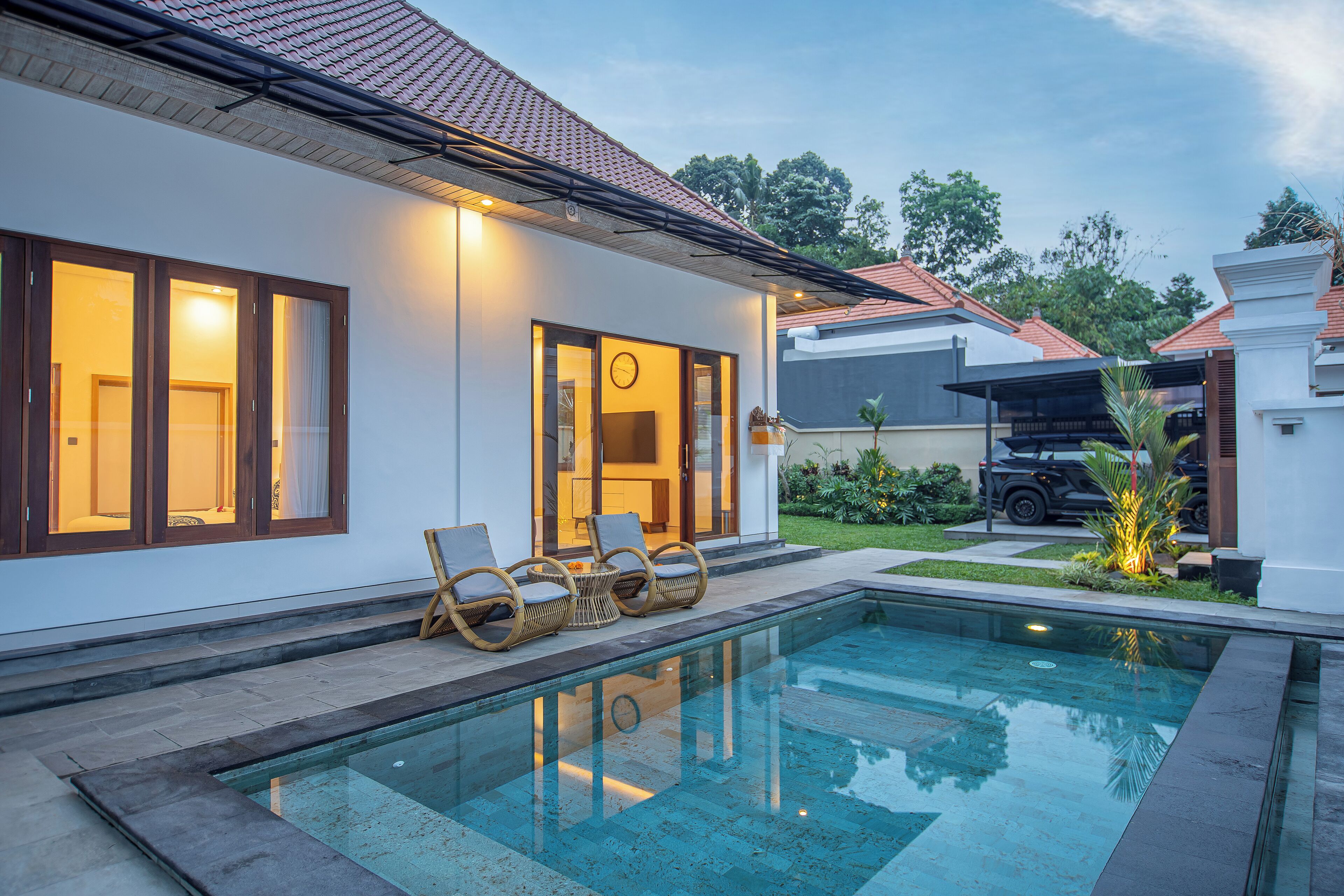 A modern house with a swimming pool, outdoor seating, and a vehicle parked outside.