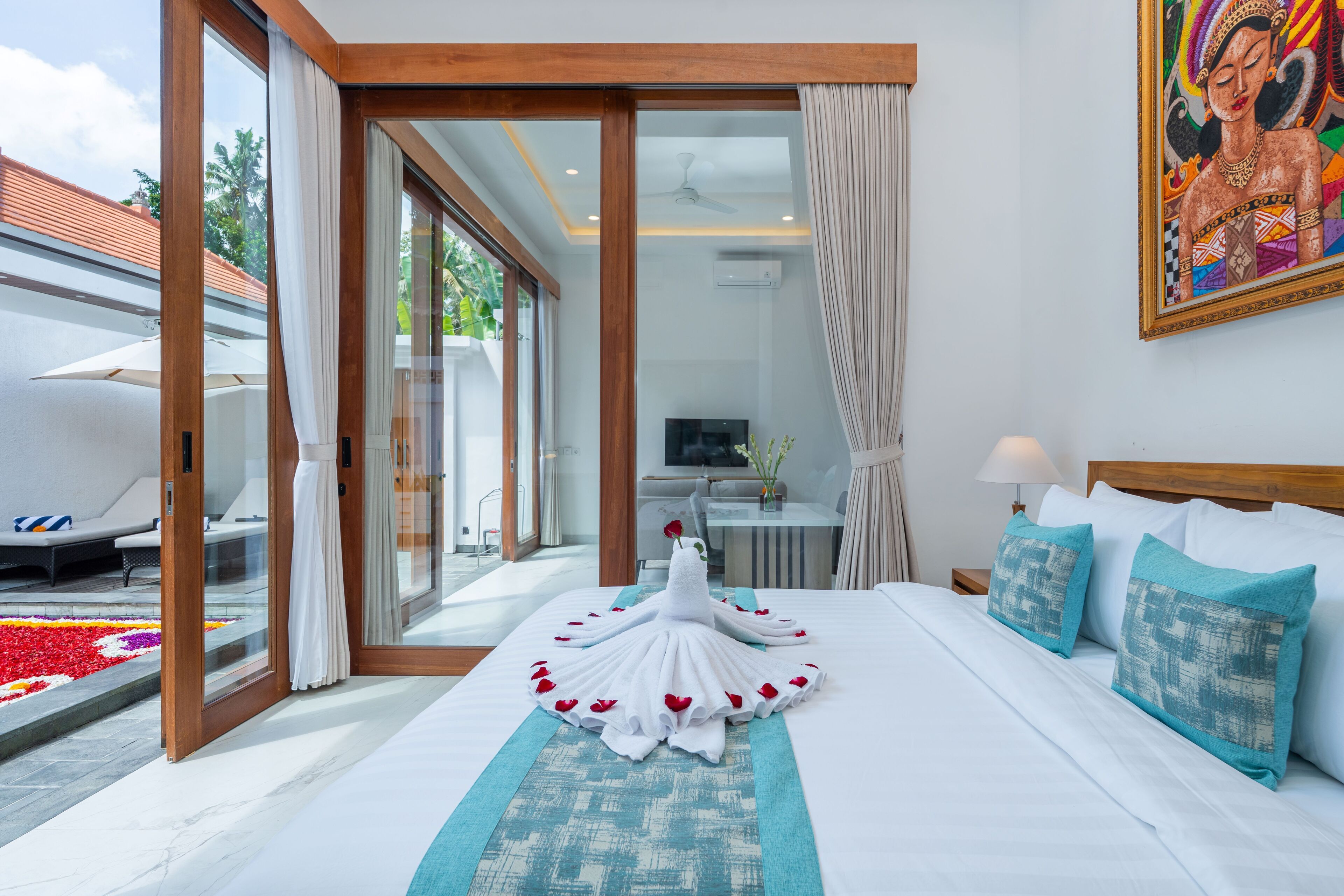 A hotel room with a bed, a desk, a TV, and a view of the outdoors.