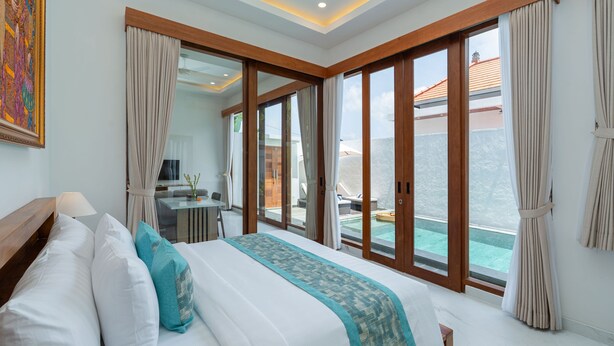 Habitación de hotel con una cama grande, un escritorio y vistas a una piscina y un balcón.