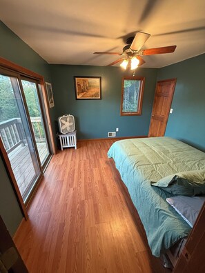 Une chambre à coucher avec un lit, un ventilateur de plafond, une fenêtre et une porte.
