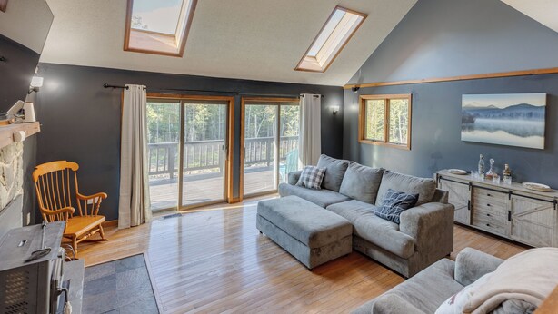 A modern living room with a sectional sofa, a wooden rocking chair, and a fireplace.