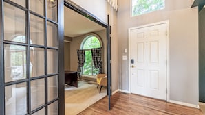 A room with a wooden floor, a white door, and a window with curtains. - Spacious Centennial 4BR with Pool Table and Patio (Centennial)