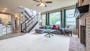A spacious living area with a staircase, a fireplace, and a large window. - Spacious Centennial 4BR with Pool Table and Patio (Centennial)