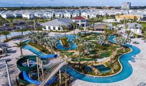 Un complex turístic amb diversos edificis, una àmplia zona de piscina amb tobogans i un camp de golf.
