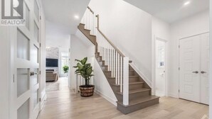 Ein modernes Interieur mit Treppe, Holzboden und weißen Wänden.