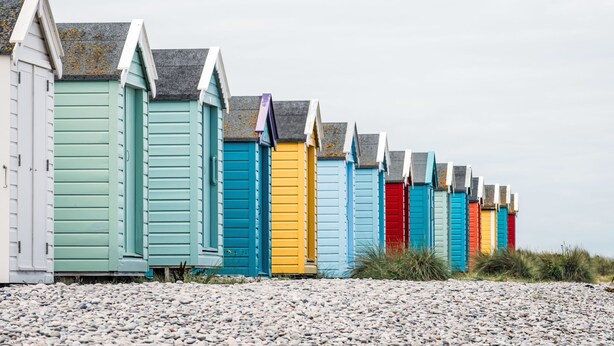 A row of colorful beach huts with sloped roofs and white trim, lined up on a pebbled beach. - Varis Haven by Interhome (Forres)
