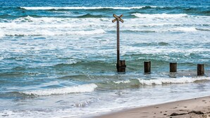 A beach with a wooden cross in the water, surrounded by wooden posts. - Varis Haven by Interhome (Forres)