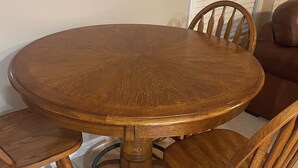 Une table de salle à manger ronde en bois, accompagnée de quatre chaises assorties.