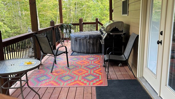 A covered outdoor deck with a ceiling fan, a barbecue grill, and a seating area with chairs and a table. - Quiet, relaxing, Guest House with large porch on Cagle Mountain in Dunlap, Tn. (Dunlap)