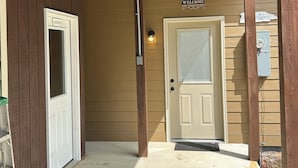 A wooden porch with a 'Welcome' sign, a door labeled 'Laundry', and a utility box on the wall. - Quiet, relaxing, Guest House with large porch on Cagle Mountain in Dunlap, Tn. (Dunlap)