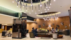 A modern lobby with a curved ceiling, hanging pendant lights, and a seating area with sofas and a coffee table. - Shore 2 with balcony Near Mall of Asia. (Pasay)