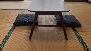 Ein Raum mit Tatami-Matten, einem niedrigen Tisch und Schiebetüren.