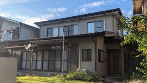 Ein zweigeschossiges Wohnhaus mit überdachter Terrasse, Garage und kleinem Garten.