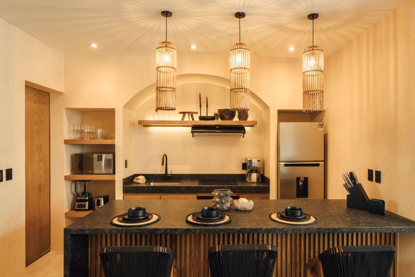 A modern kitchen with a central island, pendant lights, and a built-in refrigerator.