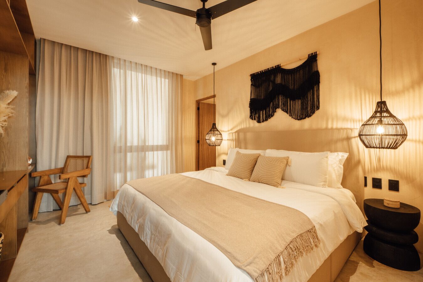 Ein geräumiges Schlafzimmer mit einem großen Bett, einem Holzstuhl und einem Deckenventilator.