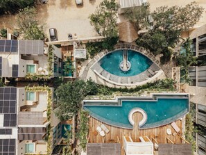 A rooftop pool with a circular design, surrounded by lush greenery and modern buildings. - 1 BR Jungle Elixir w private pool n concierge (Tulum)
