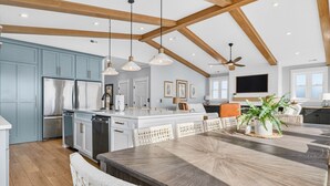 Una cocina amplia con una isla grande, vigas de madera e iluminación colgante.