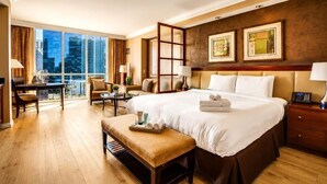 A hotel room with a large bed, a desk, a chair, a bench, and a view of the city.