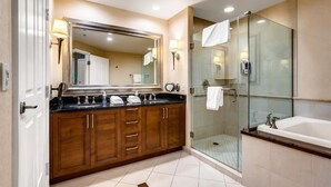 A modern bathroom with a large mirror, a glass shower enclosure, and a separate bathtub.