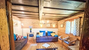 Ein gemütliches Blockhaus-Interieur mit einer Couch, einem Sessel, einem kleinen Tisch und einem Servicewagen.