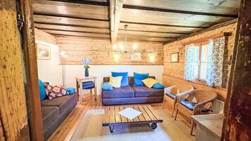 A cozy log cabin interior with a sofa, a chair, a small table, and a cart.